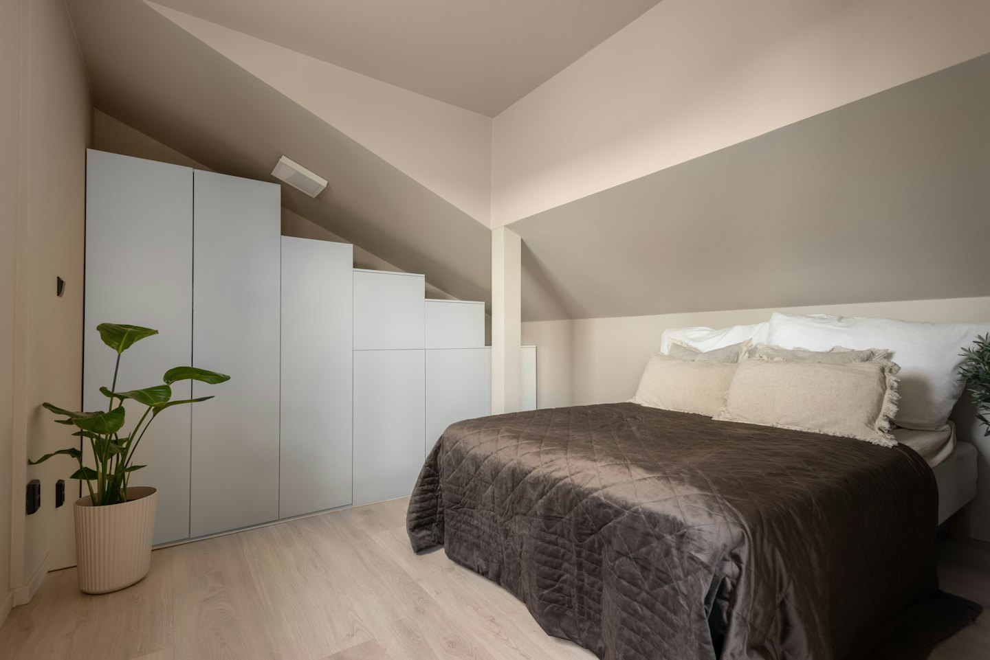 Modernes Schlafzimmer mit dunkler Steppdecke und Einbauschränken.