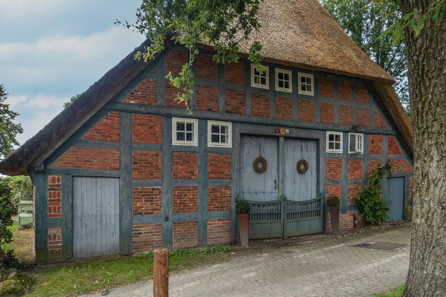 Ein traditionelles Fachwerkhaus mit Reetdach und deutschem Text.