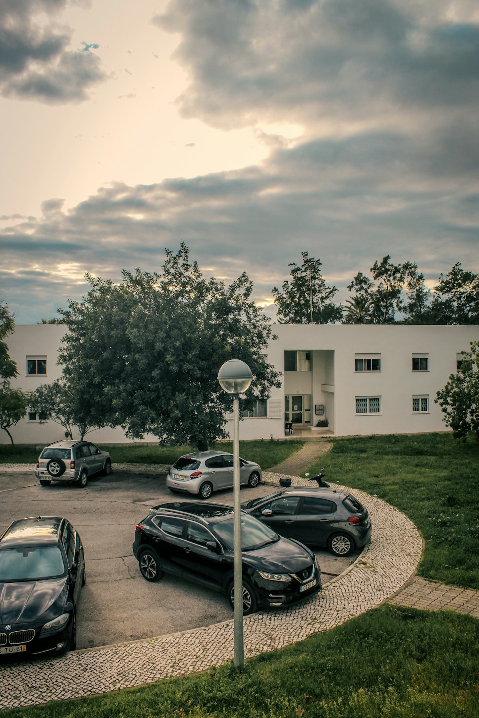 Autos vor einem modernen weißen Wohnhaus.