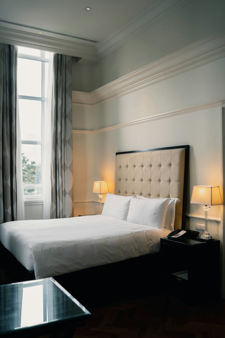 Hotelzimmer mit großem Bett und warmen Lampen.