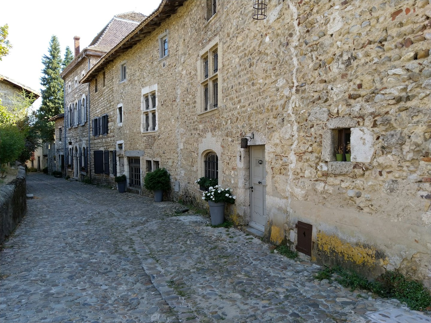 Kopfsteinpflasterstraße mit historischen Steingebäuden in einem Dorf.