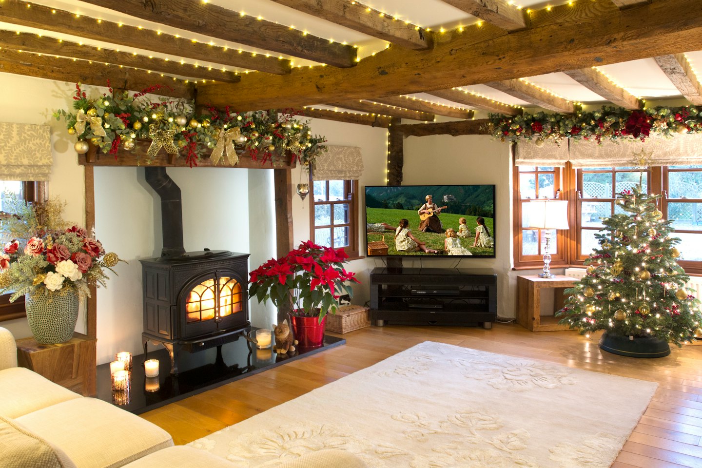 Weihnachtliches Wohnzimmer mit beleuchtetem Holzofen und geschmücktem Baum.