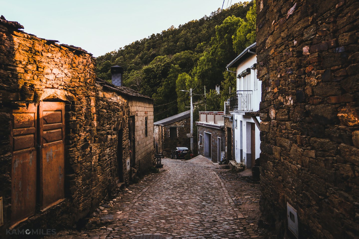 Kopfsteinpflasterstraße führt durch ein historisches Steindorf.