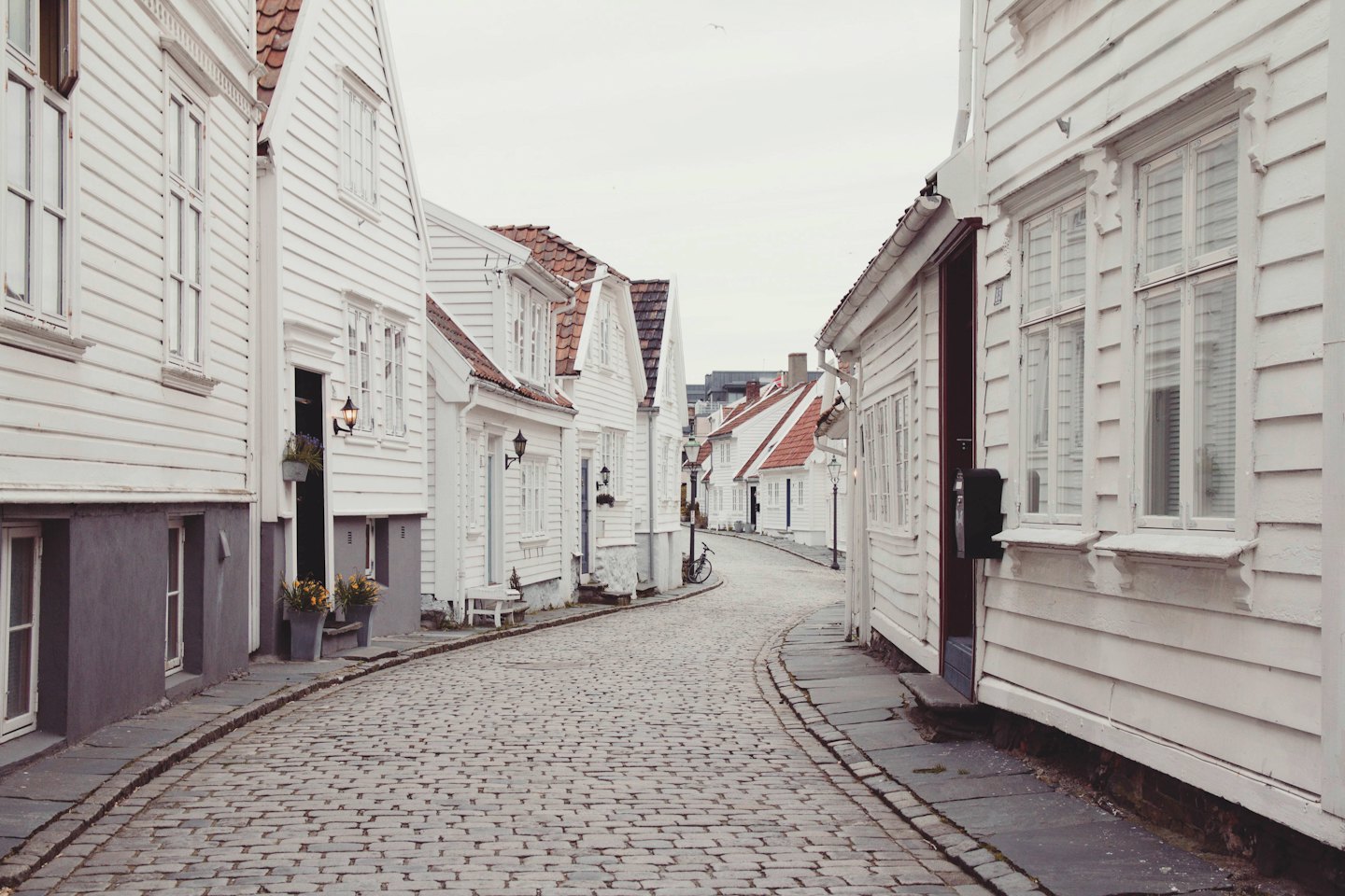 Kopfsteinpflasterstraße in einem historischen Dorf mit Holzschindelfassaden.