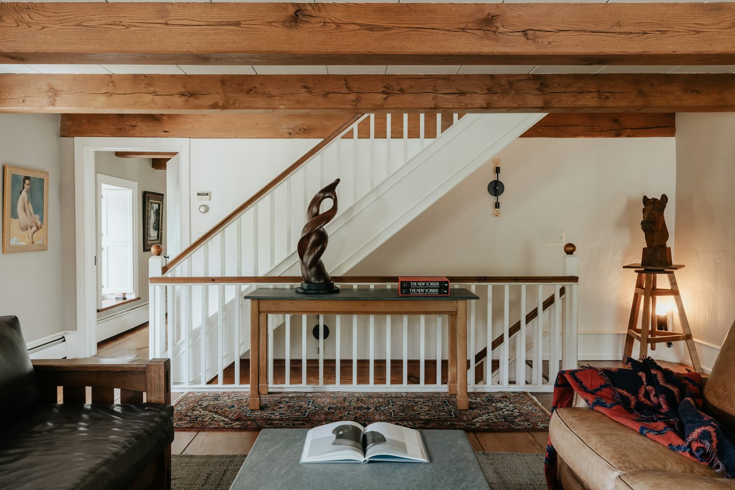 Rustikales Wohnzimmer mit weißer Treppe und Ledersitzen.