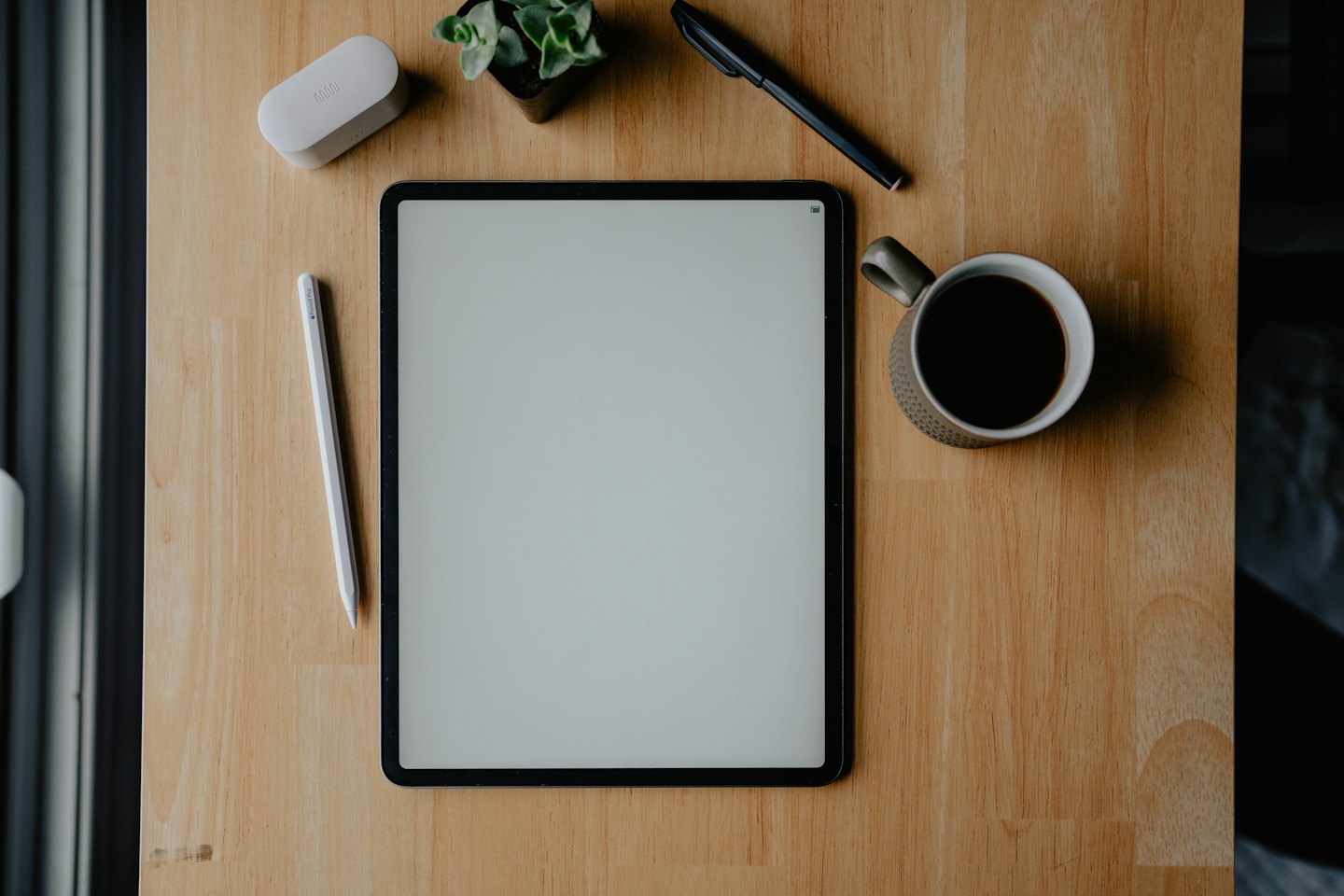 Tablet und Büromaterial auf einem Holztisch.